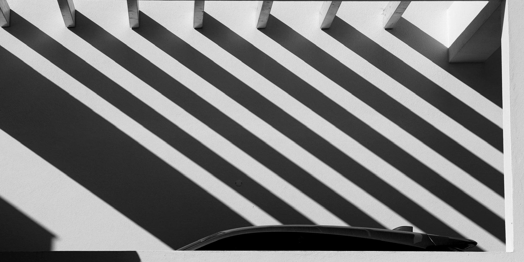 Diagonal shadows cast across a white wall, an image of structure and order